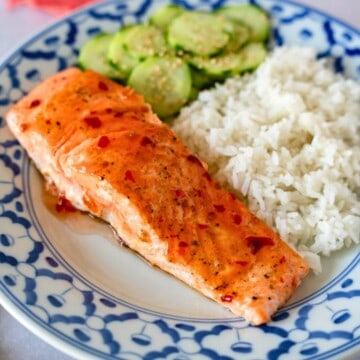 Feature image of sweet chili salmon on a plate with rice and cucumbers.