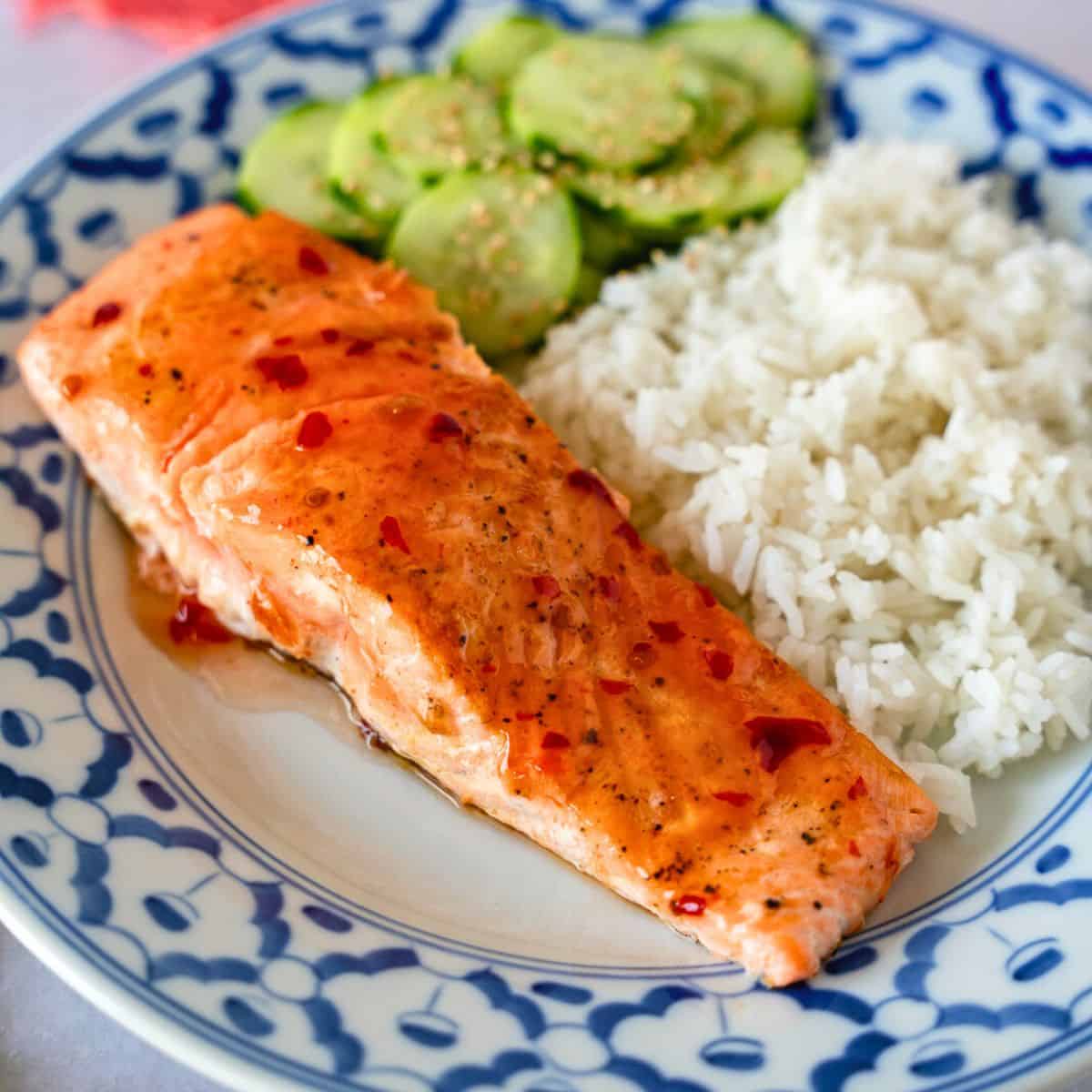 Feature image of sweet chili salmon on a plate with rice and cucumbers.