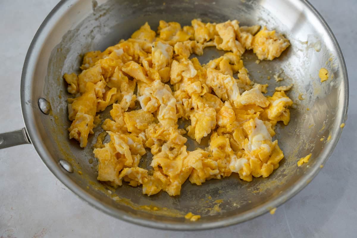 Scrambled eggs in a stainless steel skillet.