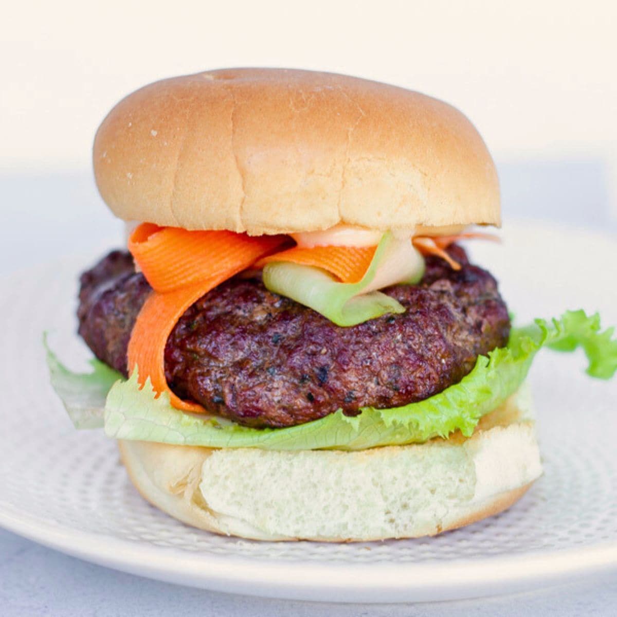 Feature image of a burger with ribbons of carrots and cucumbers.