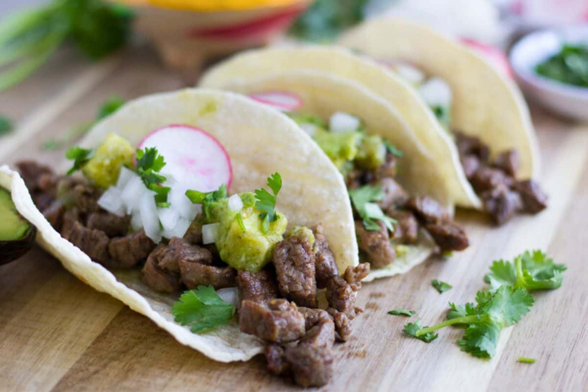 Carne asada tacos on a cutting board.