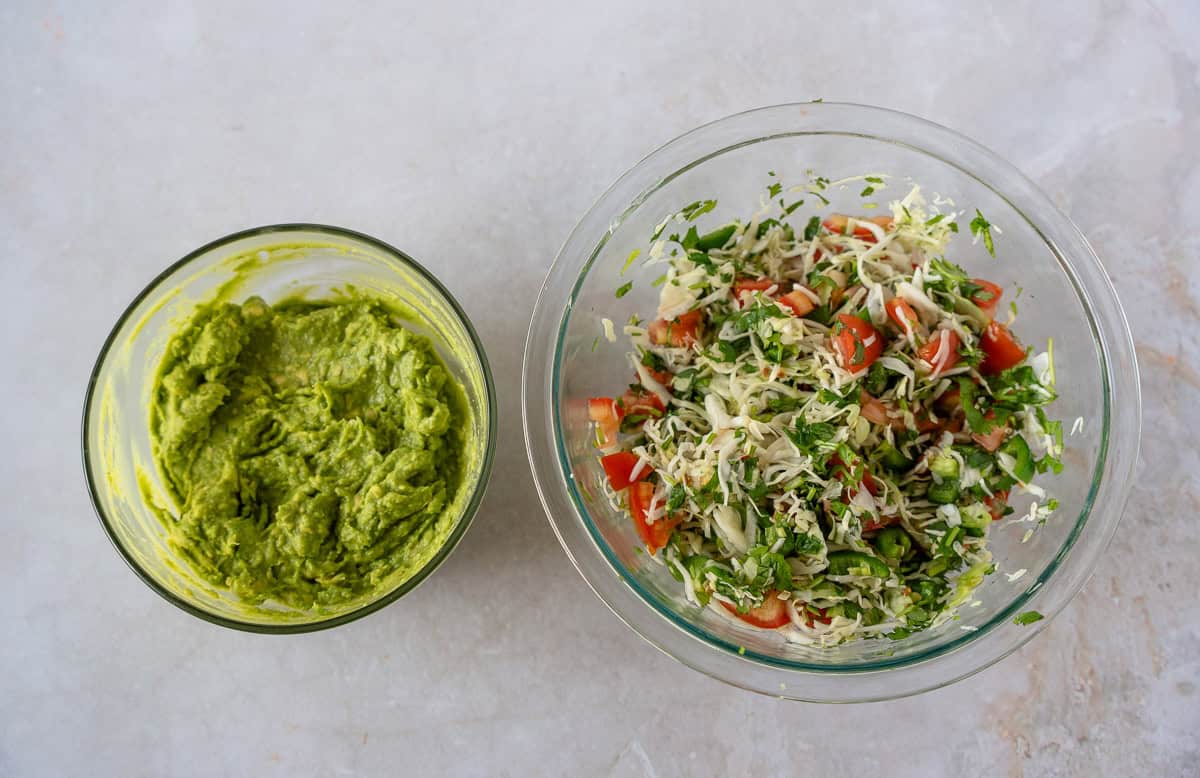 One bowl with guacamole and another with cabbage slaw.
