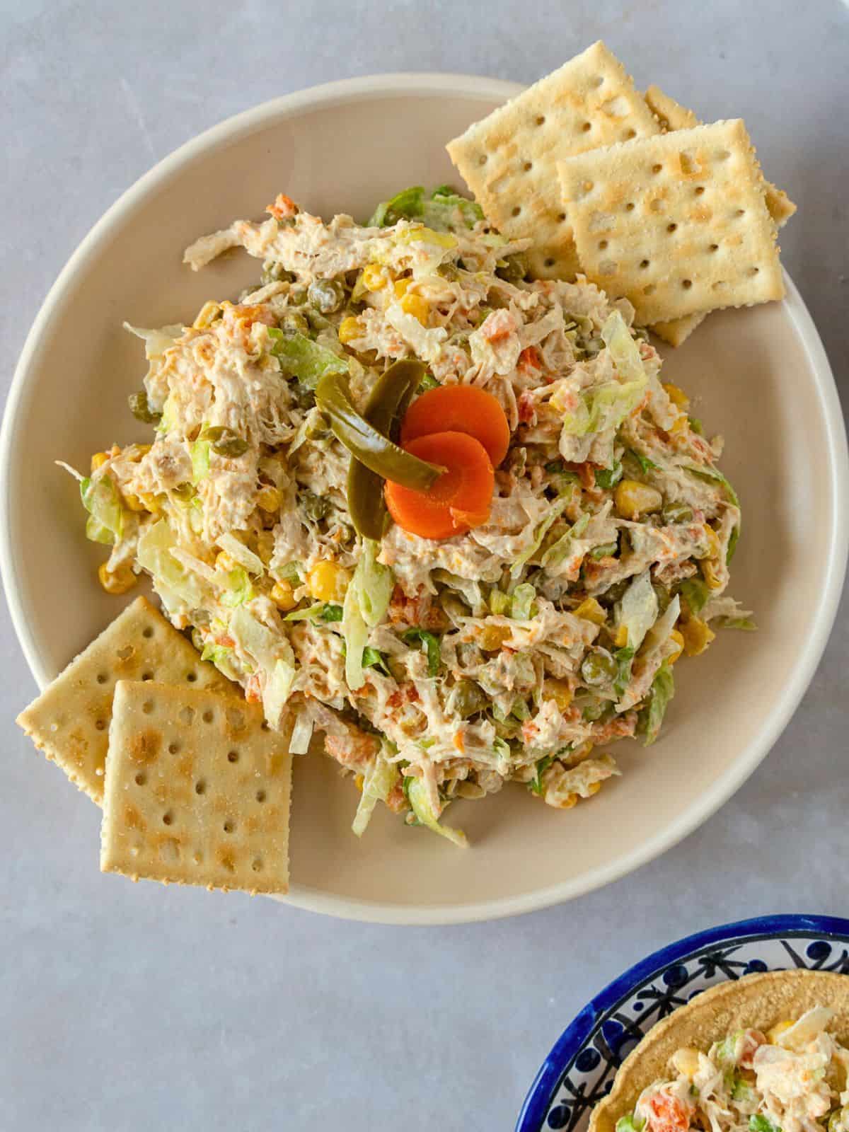 Chicken salad on a plate with saltines on the side.
