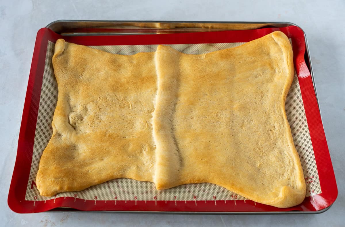 A baking sheet with a piece baked crescent dough.