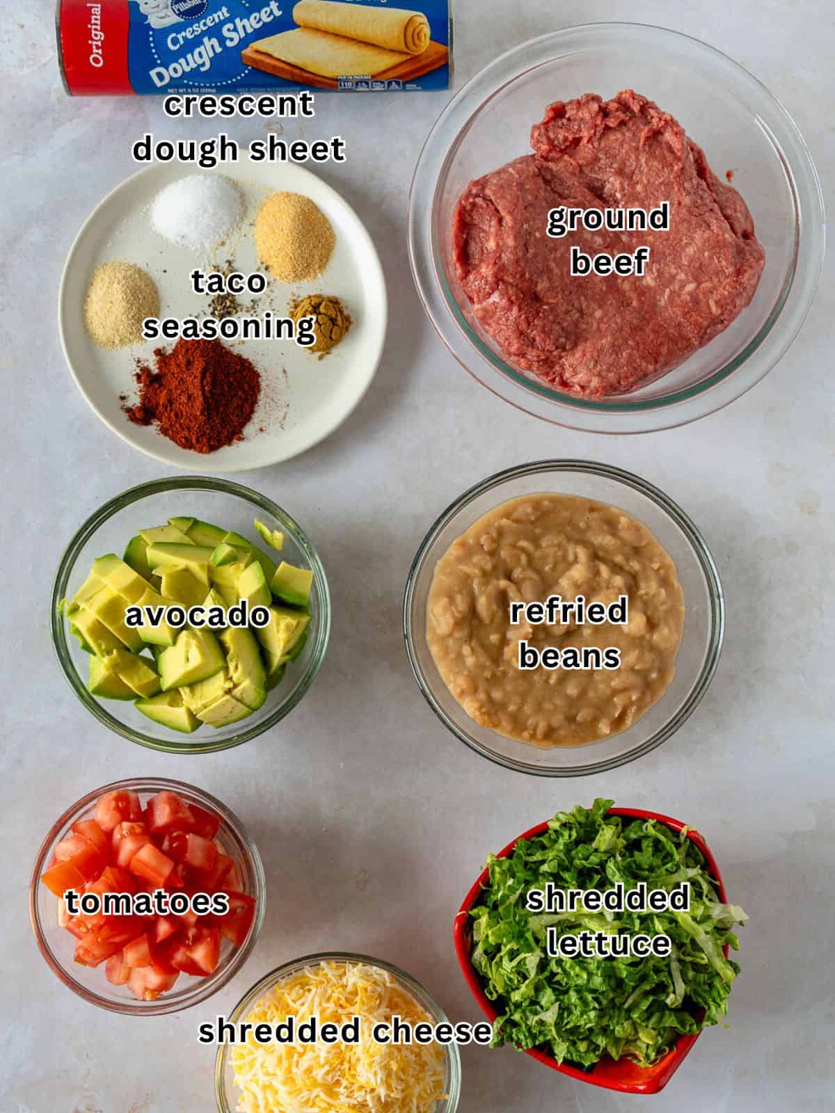 The ingredients for a taco pizza are laid out on a table.