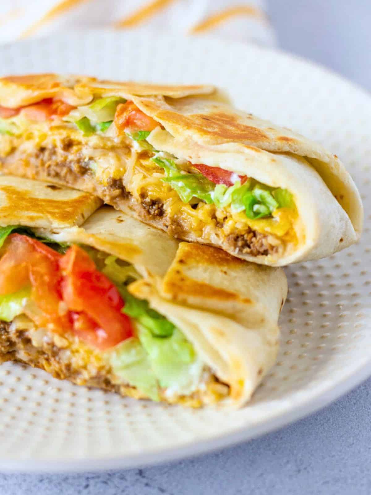 Crunchwrap cut in half and layered on top of each other on a plate.