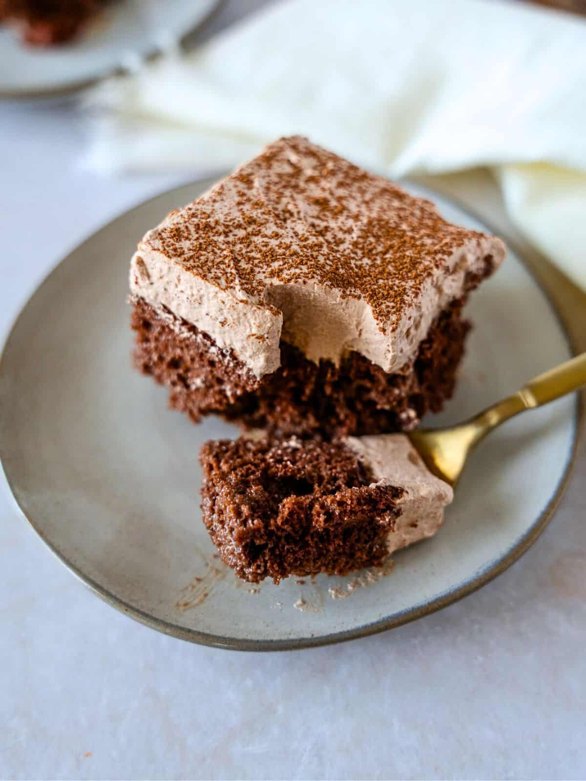 A piece of cake scooped with a gold fork.