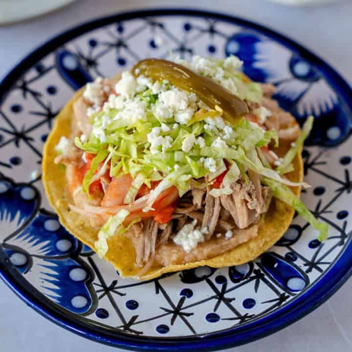 Feature image of a pork tostada on a blue plate.