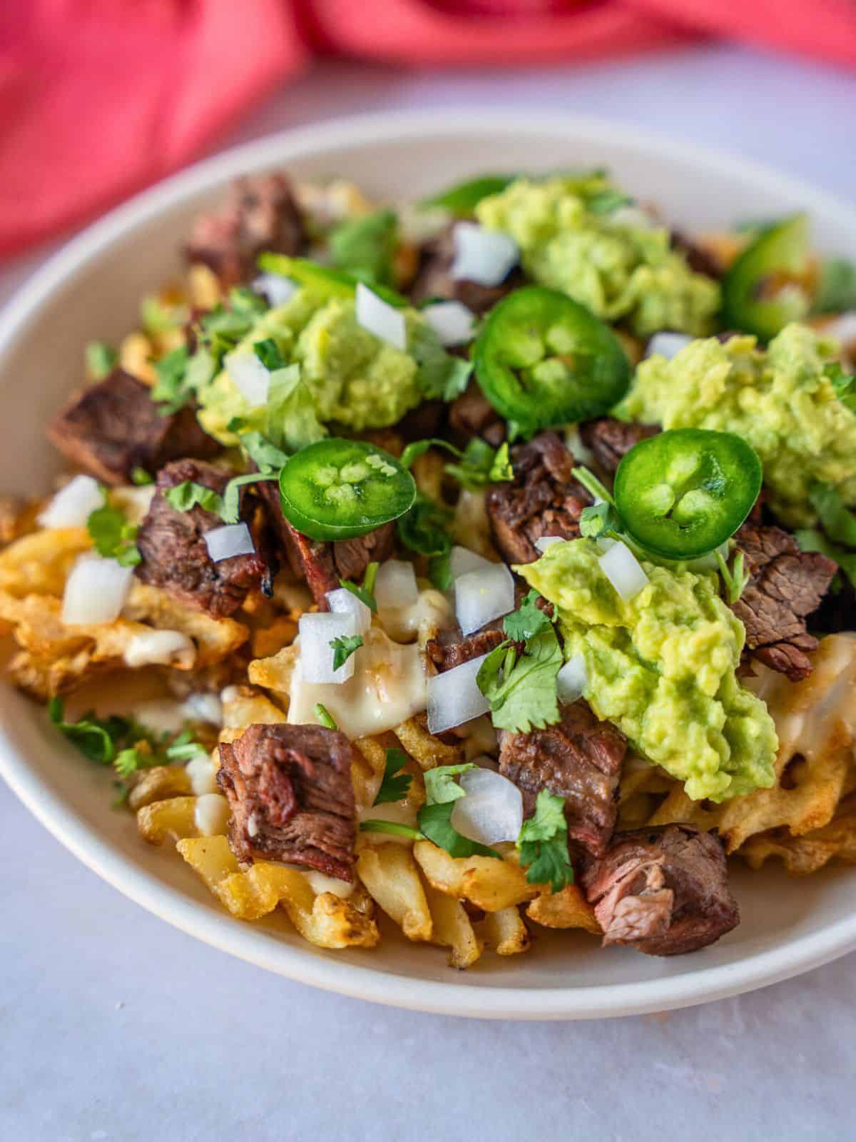 Waffle fries topped with queso, carne asada, guacamole, jalapeno, onion, and cilantro.
