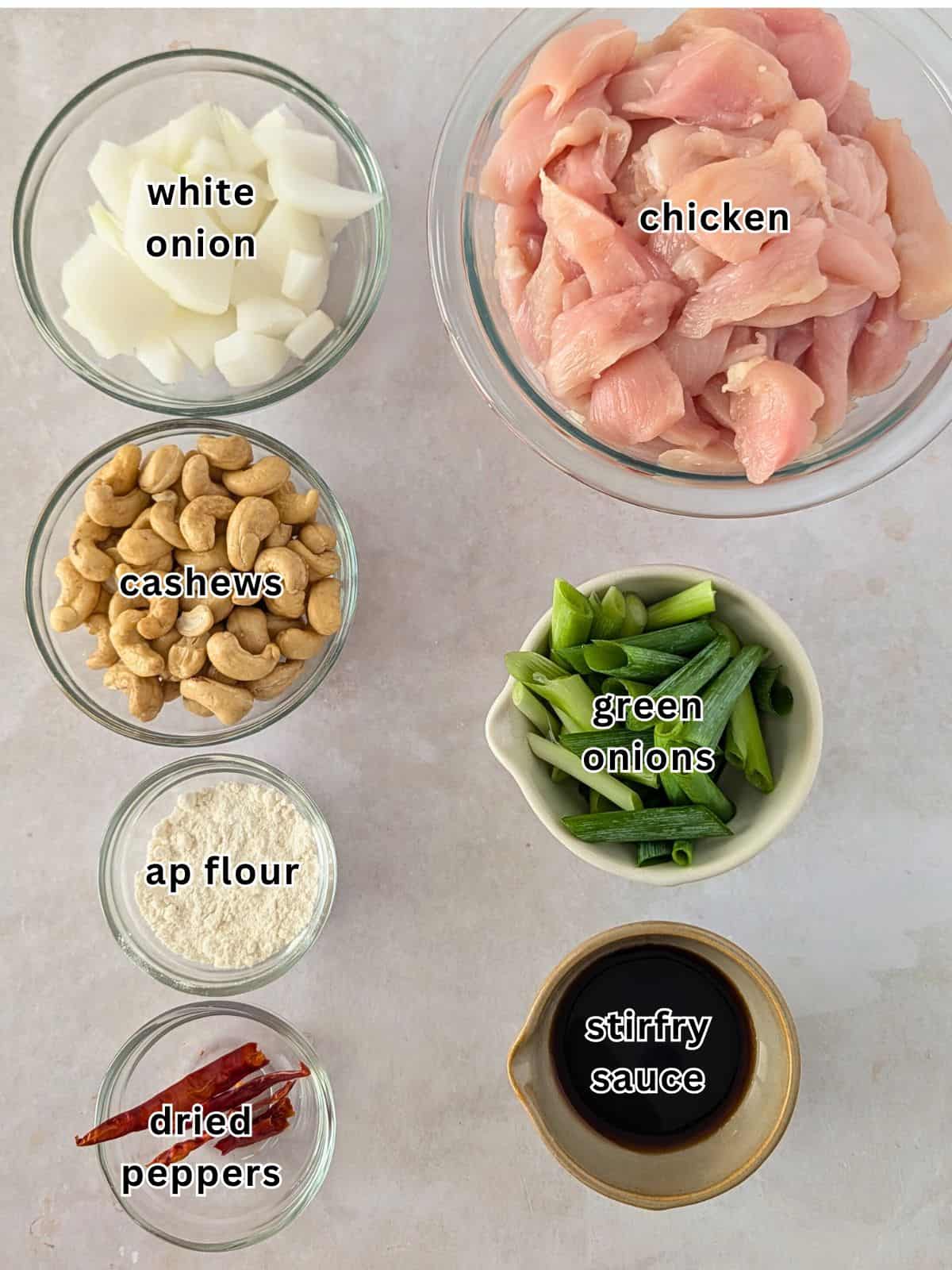 Ingredients with text- white onion, cashews, ap flour, dried peppers, chicken, green onions, stir fry sauce.