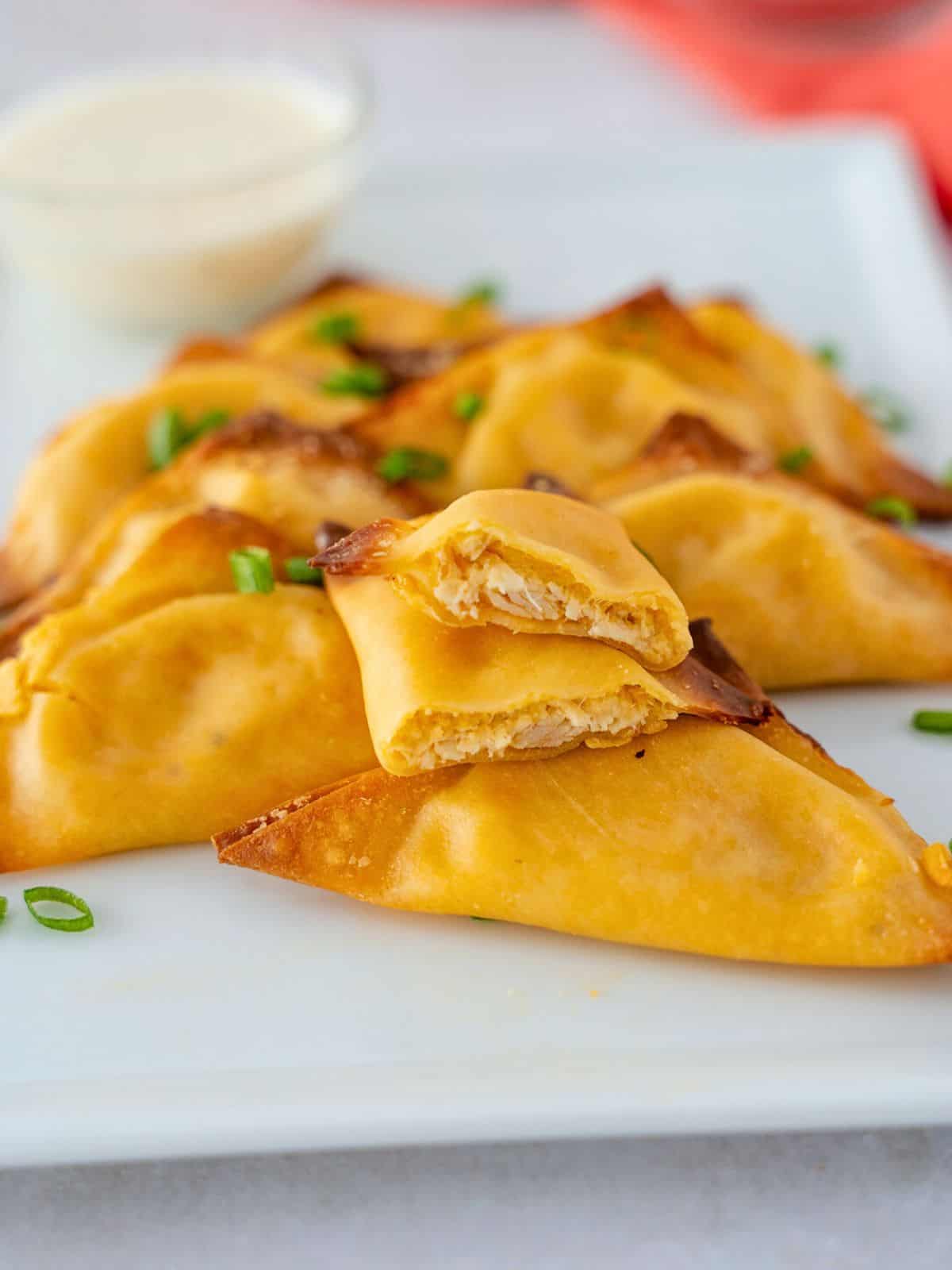 Buffalo wontons on a plate with one cut in half to see the center.