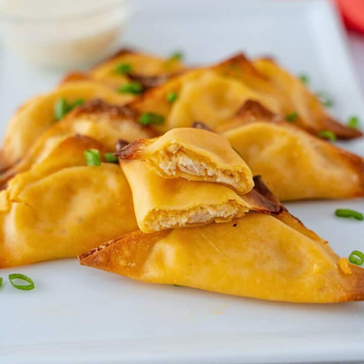 Feature image of buffalo wontons on a plate with one cut in half to see the center.
