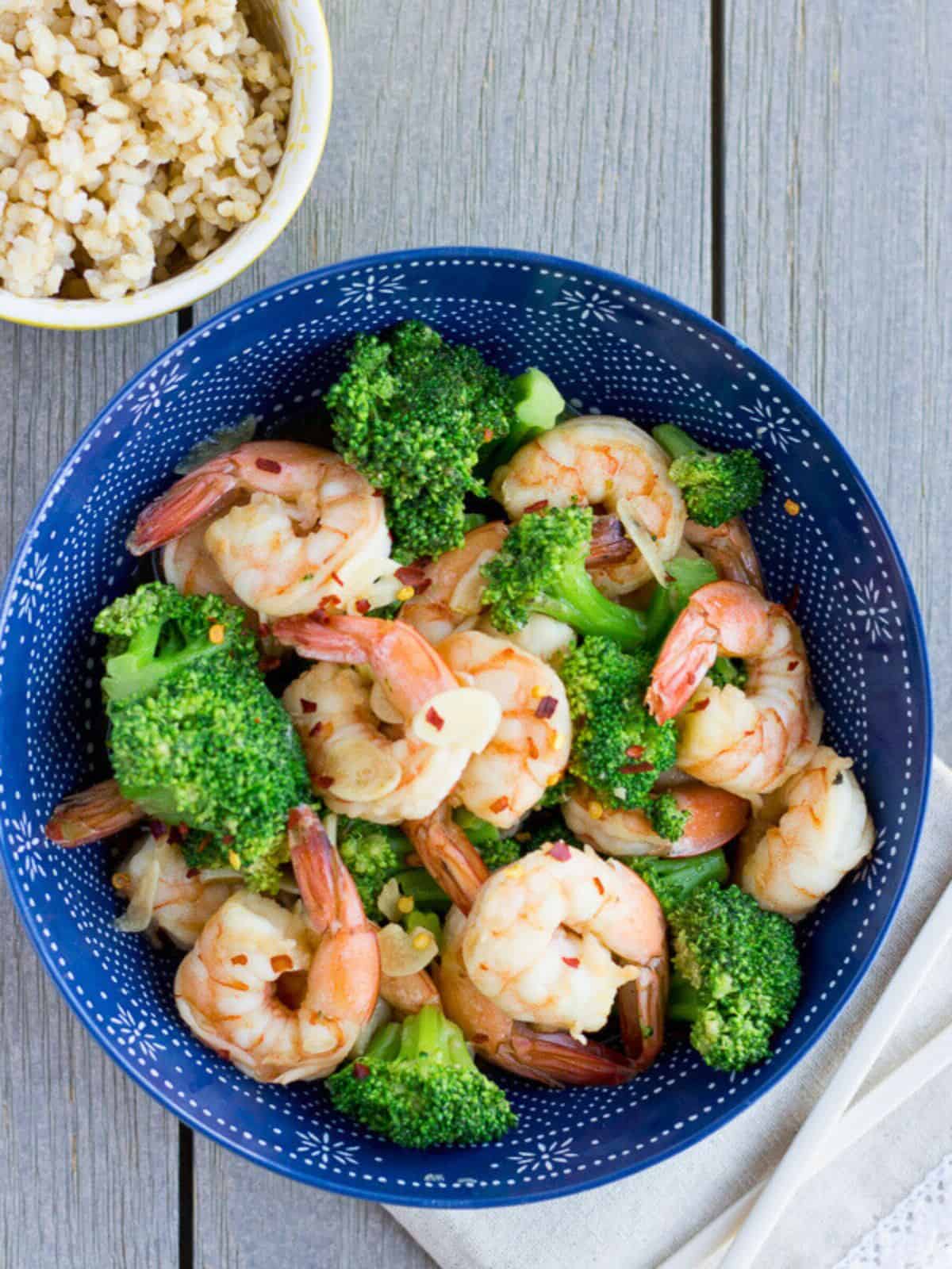 Overhead view of shrimp and broccoli stir fry with a side of rice.