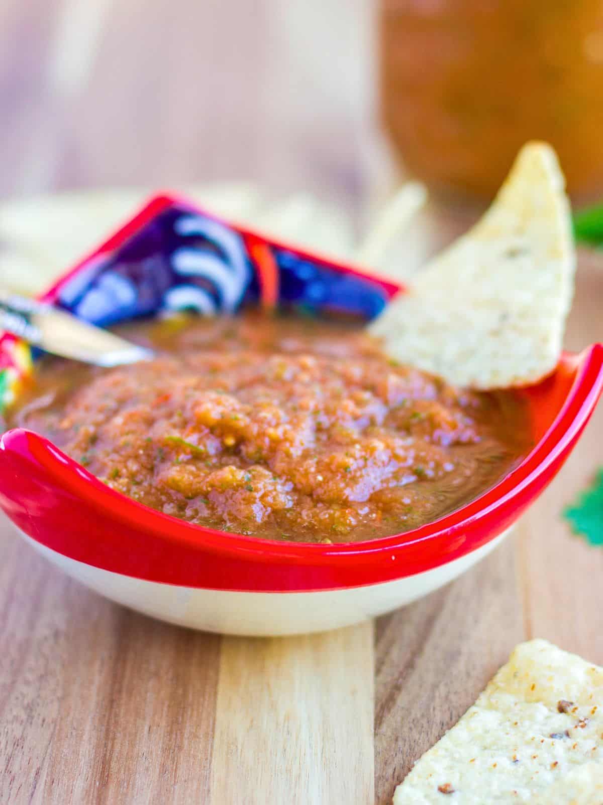 Thai salsa in a red bowl with a tortilla chip.