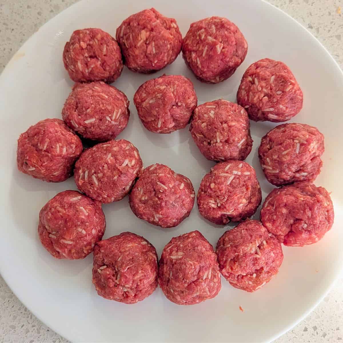 Uncooked meatballs on a plate.