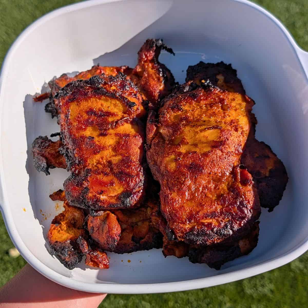 Grilled marinated pollo asado in a white dish.