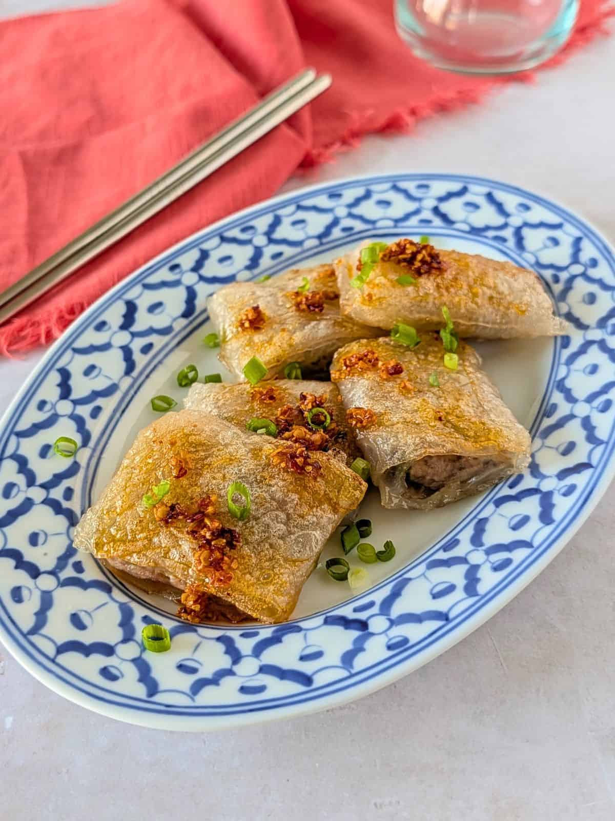Crispy rice paper dumplings on a plate with chili oil and chopped green onions.