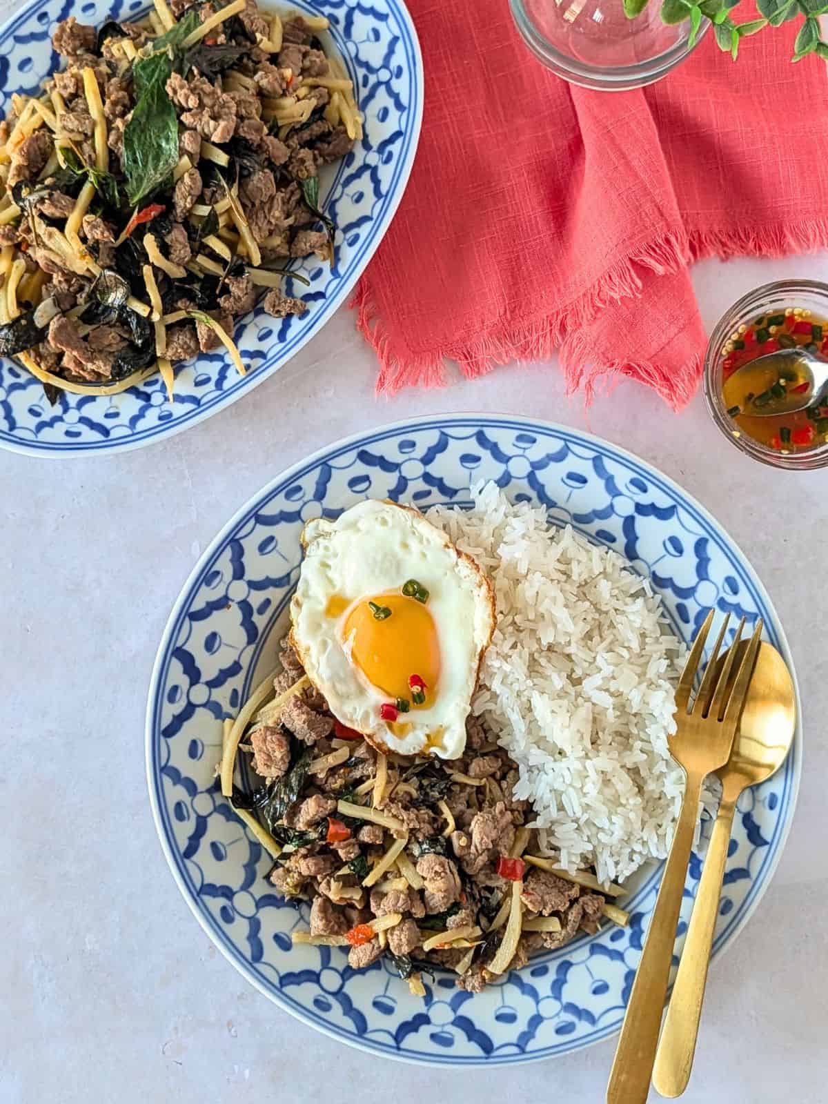 Overhead view of two plates of Thai basil beef with bamboo.