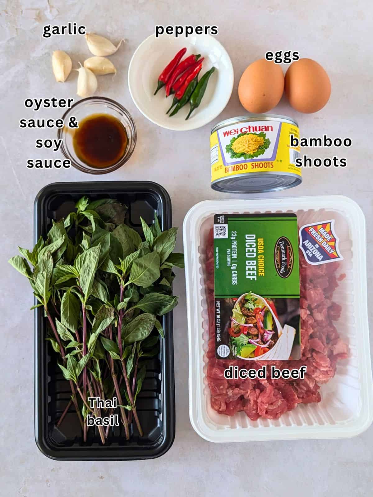 Ingredients with text- garlic, peppers, eggs, oyster sauce, soy sauce, bamboo shoots, Thai basil, and diced beef.