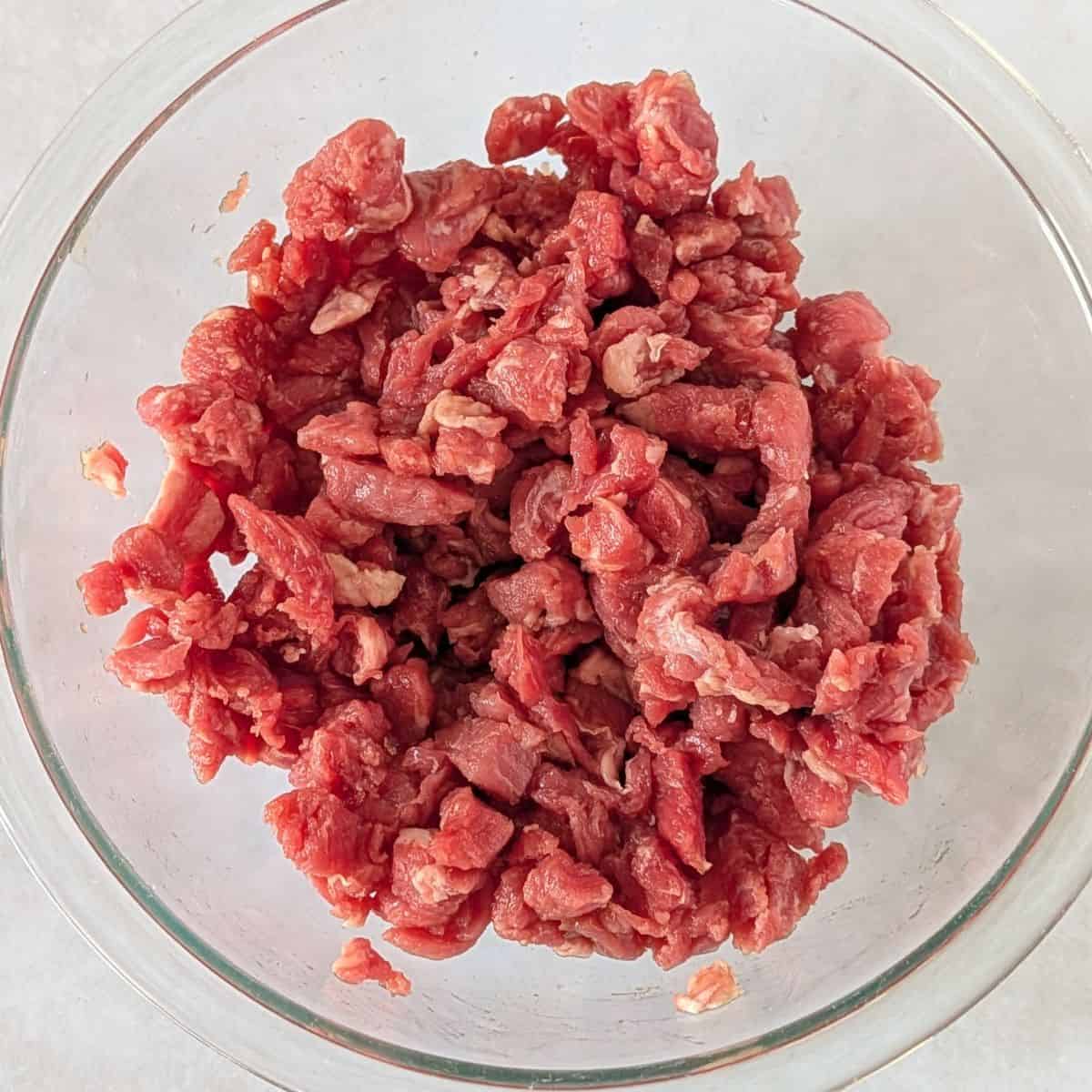 Diced beef in a glass bowl.