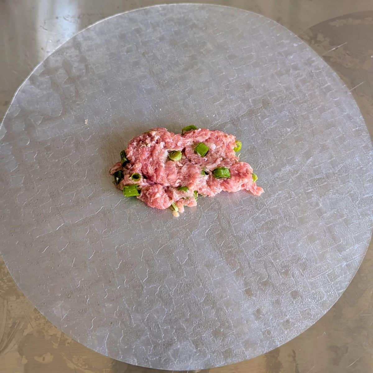 A piece of pork filling in the middle of a rice paper sheet.