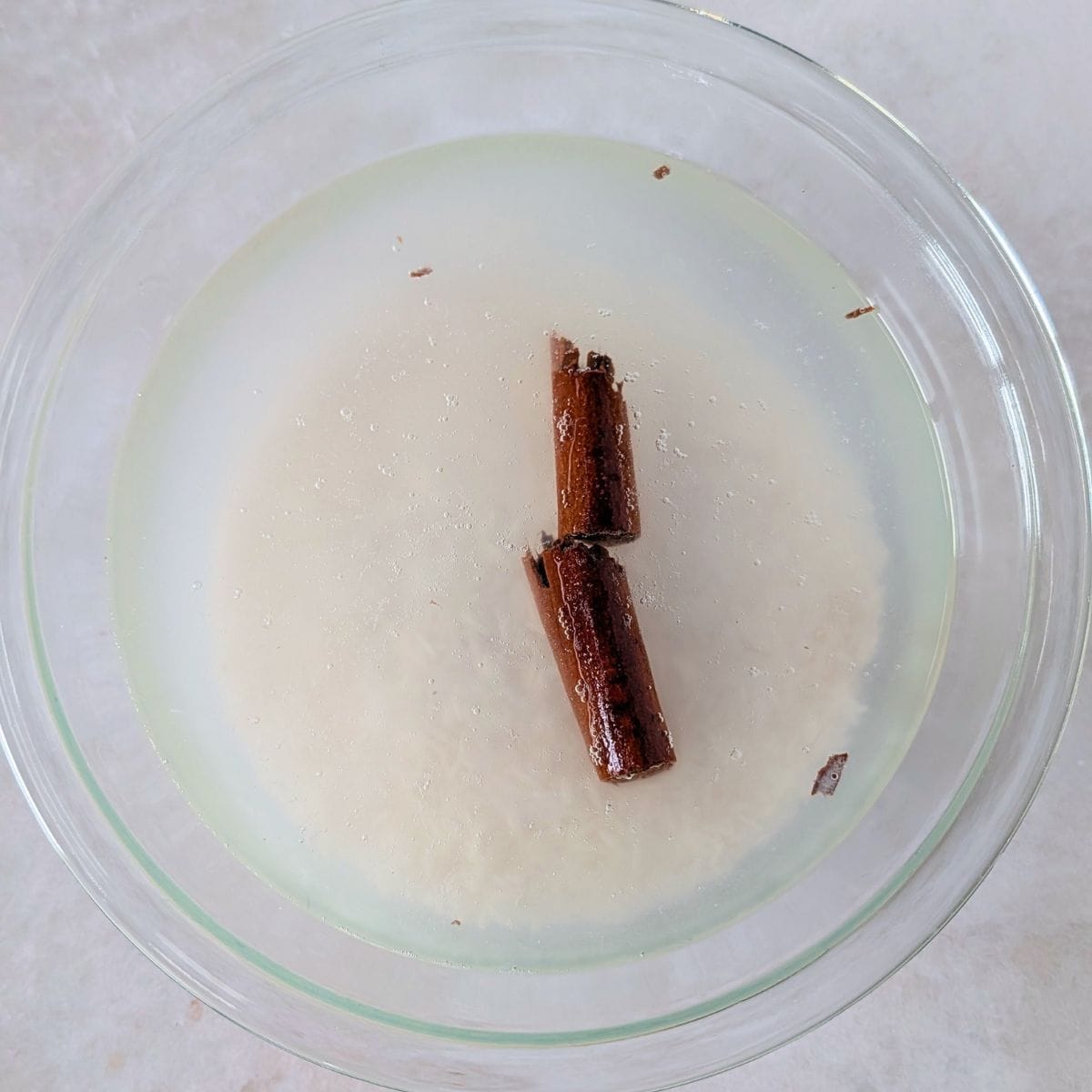 Rice and cinnamon sticks soaking in water for homemade horchata.