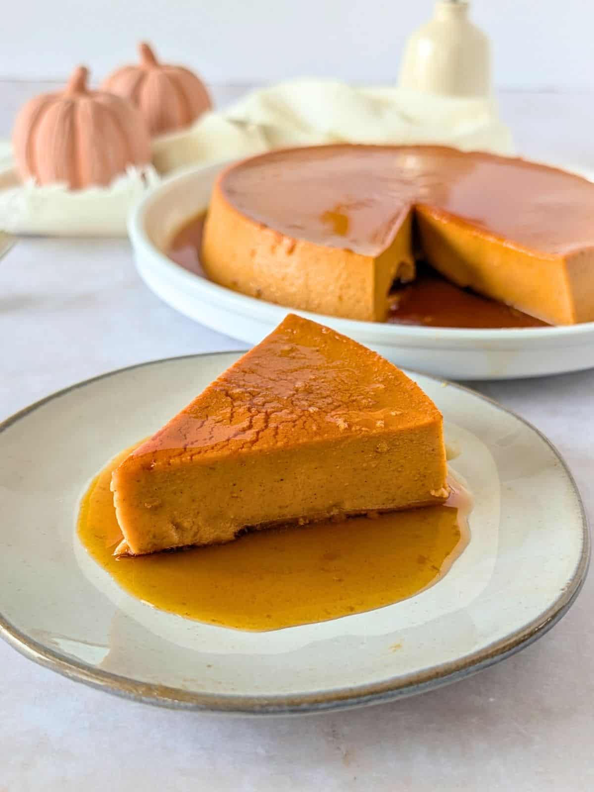 A slice of pumpkin flan on a plate with caramel sauce.