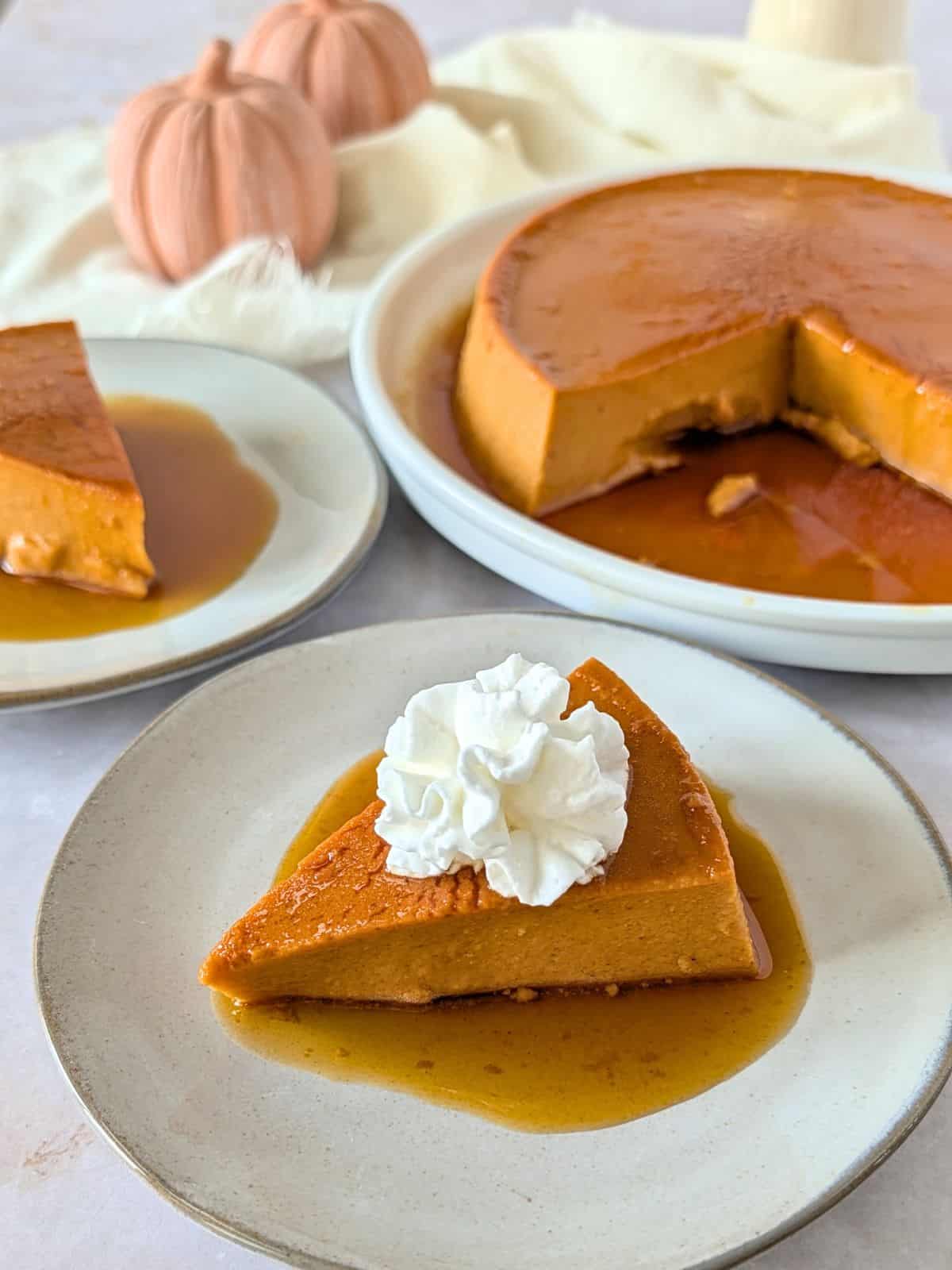 A slice of pumpkin flan on a plate topped with whipped cream.