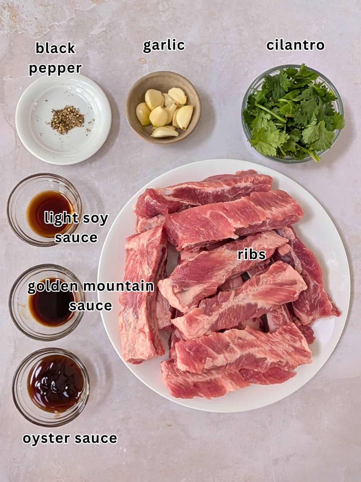 Ingredients with text- black pepper, garlic, cilantro, light soy sauce, golden mountain sauce, oyster sauce, and ribs.