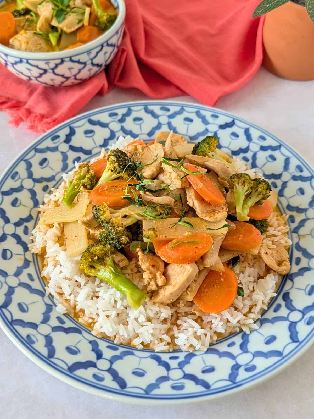 Thai red curry with chicken and vegetables on a plate over rice.